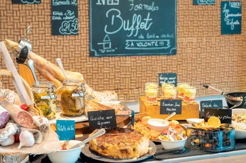 un buffet con diferentes tipos de comida en una mesa en The Originals City, Hôtel Le Pavillon, Béziers Est, en Béziers