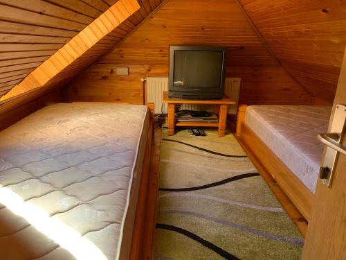 ズラティボールにあるApartman Vujovicのベッド2台とテレビ付きの屋根裏部屋