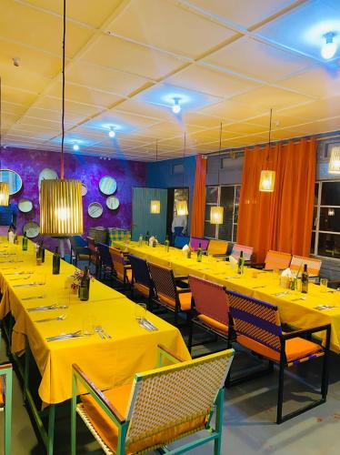 a dining room with yellow tables and chairs at Isange Paradise Resort in Ruhengeri