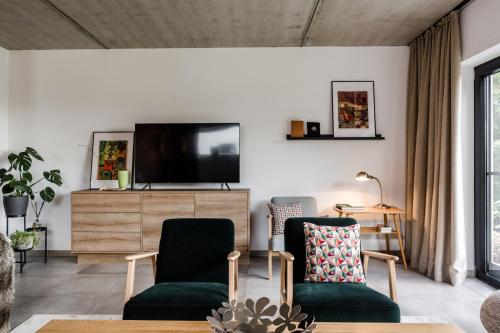 a living room with two chairs and a flat screen tv at Sommers "Schöne Aussicht", Adults only in Reichenbach im Vogtland