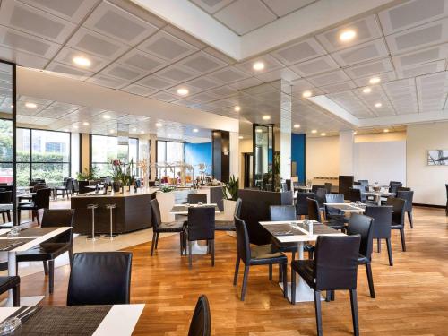 una sala da pranzo con tavoli e sedie e un ristorante di Novotel Genova City a Genova