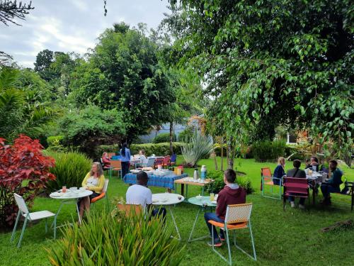 a group of people sitting at tables in a garden at Isange Paradise Resort in Ruhengeri