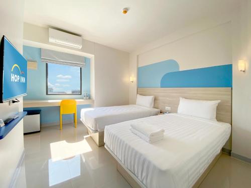 a hotel room with two beds and a desk at Hop Inn Bangkok Bangna in Bangkok