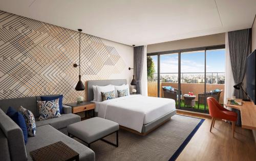 a bedroom with a bed and a living room at Hyatt Place Vadodara in Vadodara