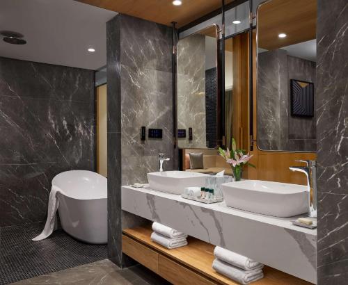 a bathroom with two sinks and a tub and a mirror at Hyatt Place Vadodara in Vadodara