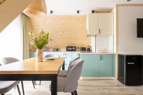 a kitchen with a wooden table with chairs and a dining room at Apartamenty Harenda Zakopane in Zakopane