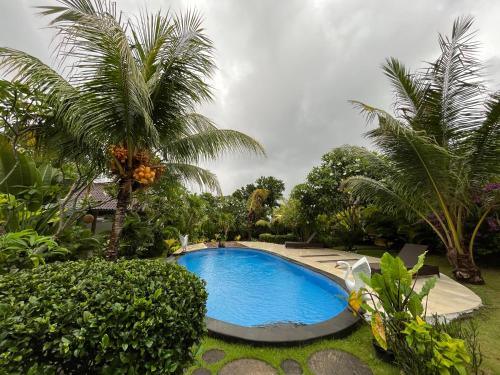 uma piscina num quintal com palmeiras em Adi's Bungalow em Uluwatu