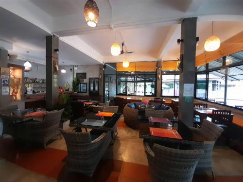 a restaurant with tables and chairs in a room at Khaolak Yama Resort - SHA Plus in Khao Lak
