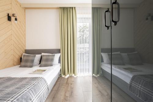 two beds in a room with a window at Apartamenty Harenda Zakopane in Zakopane