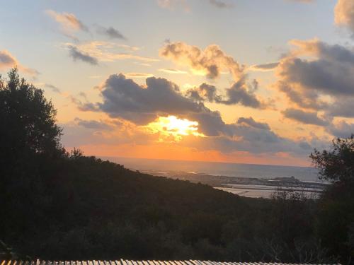 a sunset from a hill with the ocean in the background at Above the Sea in ‘En Hod