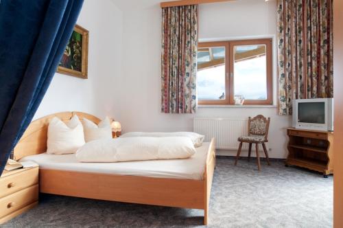 a bedroom with a bed and a tv and a window at Hotel Talhof Garni&more in Wängle bei Reutte in Reutte