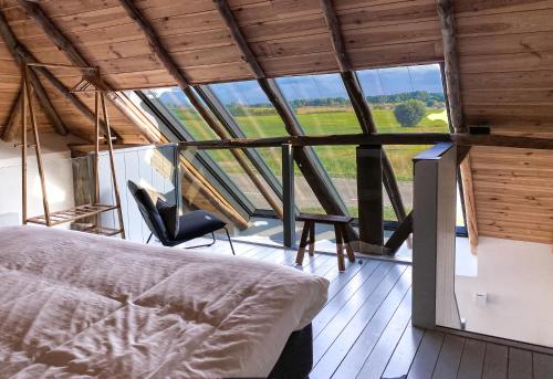 1 cama y 1 silla en una habitación con ventanas en Bissems Hofstede en Marle