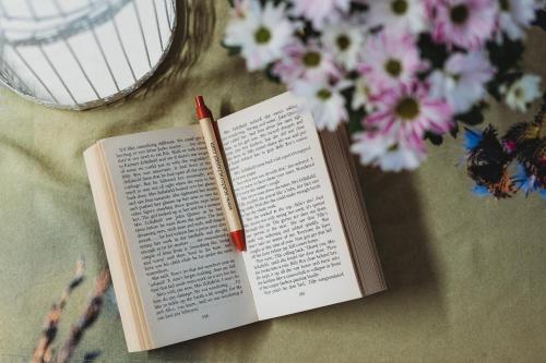 een boek met een potlood op een tafel met bloemen bij Academic Hostel in Tallinn