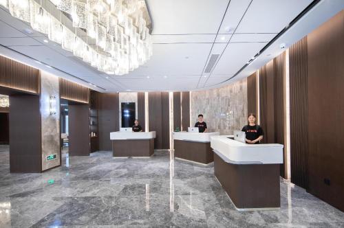a lobby with three people sitting at reception desks at Atour Hotel Anqing Municipal Affairs Center Seventh Street in Anqing