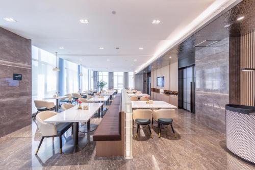 une rangée de tables et de chaises dans un restaurant dans l'établissement Atour Hotel Lianyungang Municipal Affairs Central University Town, à Lianyungang
