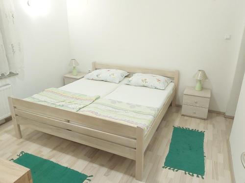 - une chambre dotée d'un lit avec des draps blancs et des tapis verts dans l'établissement APARTMENTS KRAPEC2, à Ježdovec