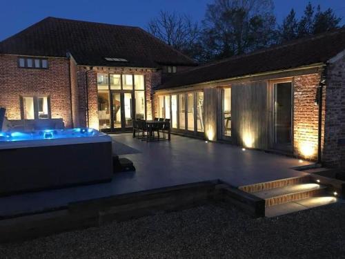a patio with a hot tub in front of a building at The Granary, Norfolk in Norwich