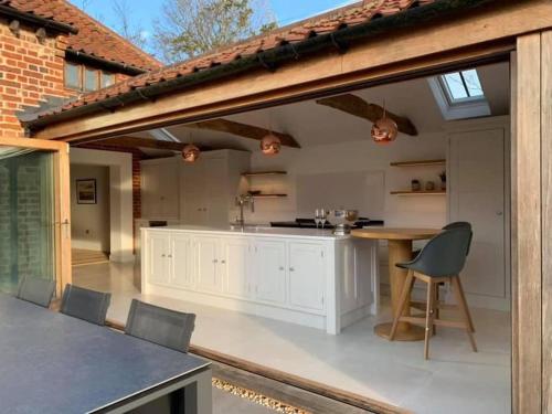 an open kitchen with white cabinets and a table and chairs at The Granary, Norfolk in Norwich