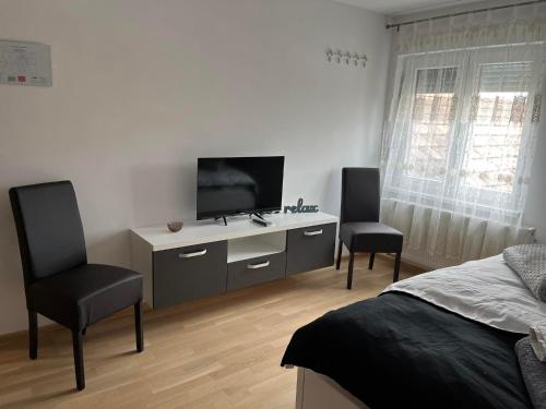 1 Schlafzimmer mit einem Bett, einem TV und 2 Stühlen in der Unterkunft Sobe Tea in Virovitica