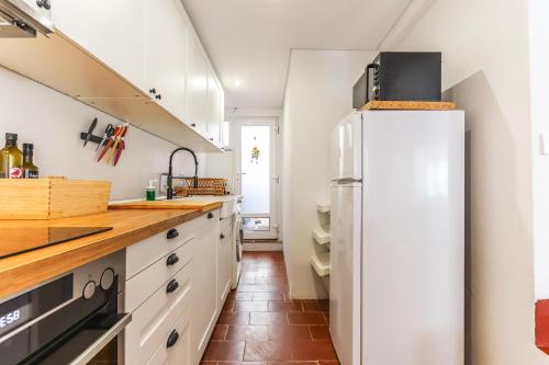 a kitchen with white cabinets and a refrigerator at Vita Portucale ! Costa Caparica Triplex w/ Terrace in Costa da Caparica