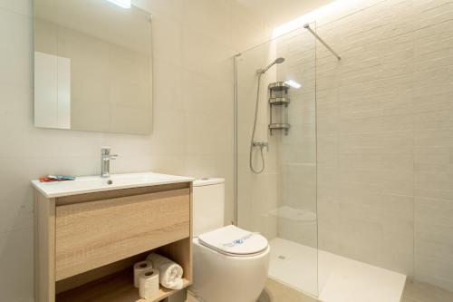 a bathroom with a toilet and a sink and a shower at Edificio Santiago by Plaza Mayor Apartamentos in Valladolid