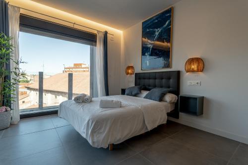 a bedroom with a large bed and a large window at Edificio Santiago by Plaza Mayor Apartamentos in Valladolid