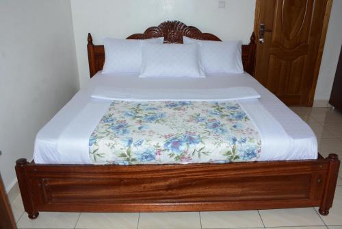 a bed with a wooden frame with a blanket on it at Corina K Guest House in Kigali