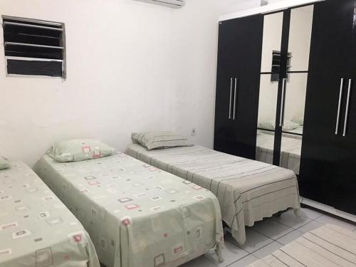 two twin beds in a room with a mirror at CASA DE TEMPORADA in Aracaju