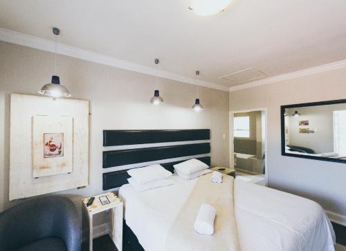 1 dormitorio con 1 cama blanca y 1 silla en B and B Sandton, en Johannesburgo