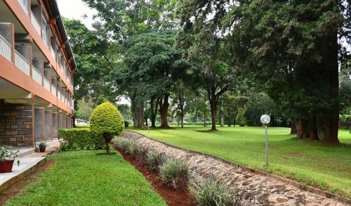a yard next to a building with trees and grass at Golf Hotel Kakamega in Kakamega