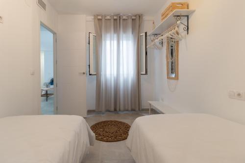 Dormitorio blanco con 2 camas y puerta en Apartamento céntrico Orive, en Córdoba