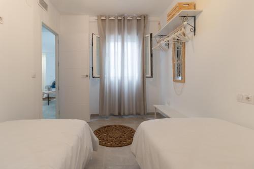 a white bedroom with two beds and a doorway at Apartamento centrico Orive in Córdoba