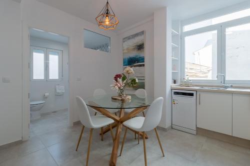 a kitchen with a glass table and white chairs at Apartamento centrico Orive in Córdoba