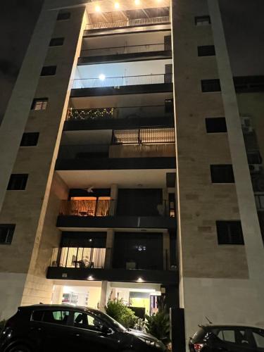 een hoog gebouw met auto's geparkeerd voor het bij Bat Yam apartment in Bat Yam