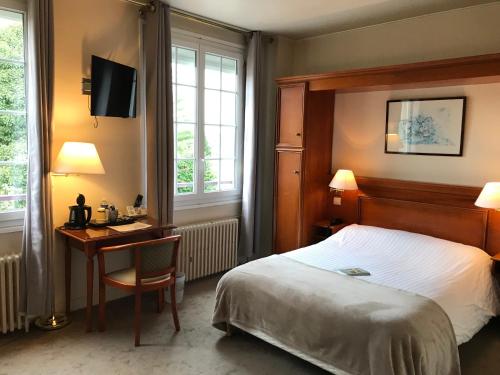 a hotel room with a bed and a desk with a computer at Logis Hôtel-Restaurant Les Airelles in Neufchâtel-en-Bray