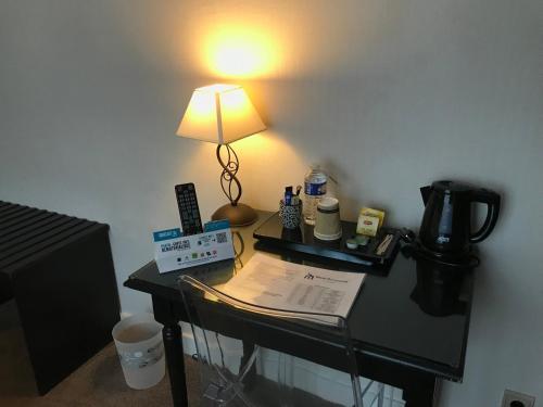 a desk with a lamp on top of it at Logis Hôtel Les Airelles Neufchâtel En Bray in Neufchâtel-en-Bray