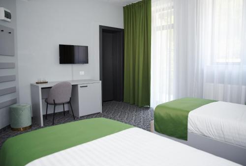 um quarto de hotel com duas camas e uma secretária em Astra Hotel em Călimăneşti