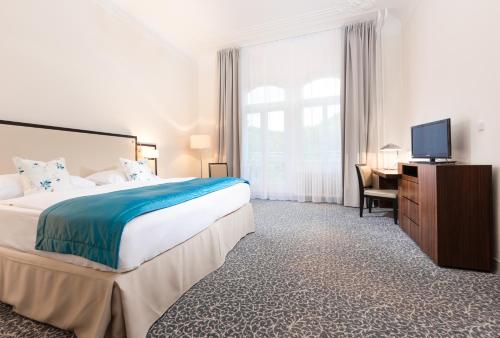 a bedroom with a bed and a desk and a television at OREA Spa Hotel Bohemia Mariánské Lázně in Mariánské Lázně