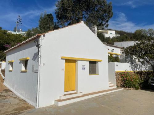 a small white building with a yellow door at Moinho Da Asneira - Duna Parque Resorts & Hotels in Vila Nova de Milfontes