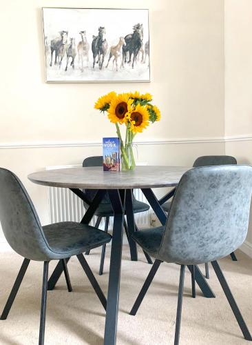 a dining room table with chairs and a vase of sunflowers at The Racecourse - Quaint Victorian Home With Free Parking in York