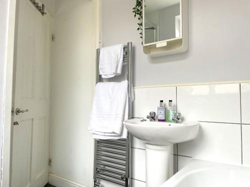 une salle de bain blanche avec un lavabo et un miroir dans l'établissement The Racecourse - Quaint Victorian Home With Free Parking, à York