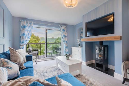 a blue living room with a blue couch and a tv at Belsfield Cottage in Bowness-on-Windermere