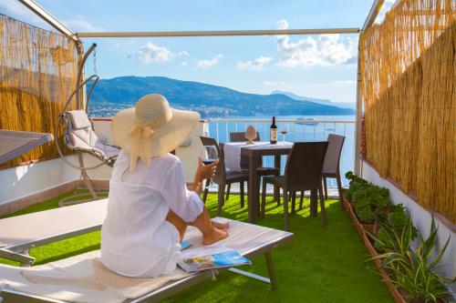a woman sitting on a balcony looking out at the water at Dreamers' Escape in Vico Equense