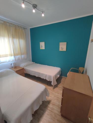 Cette chambre comprend 2 lits et un mur bleu. dans l'établissement Migjorn 6, à Deltebre