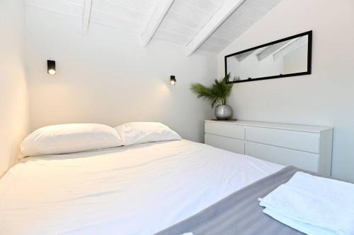 a white bedroom with a bed and a mirror at Gluck House in Migdal