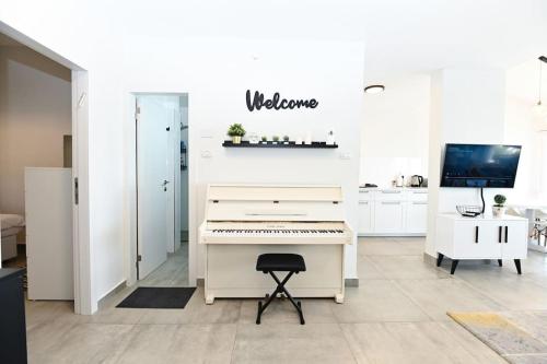 a living room with a white piano and a television at Gluck House in Migdal
