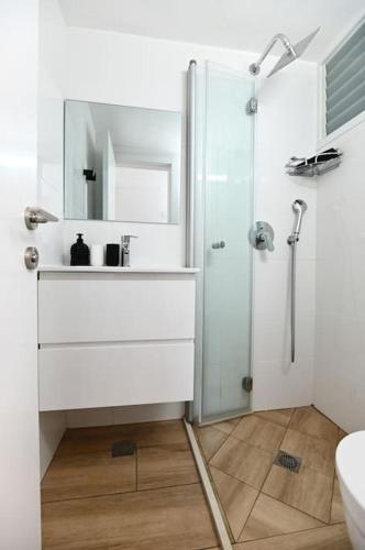 a white bathroom with a sink and a shower at Gluck House in Migdal
