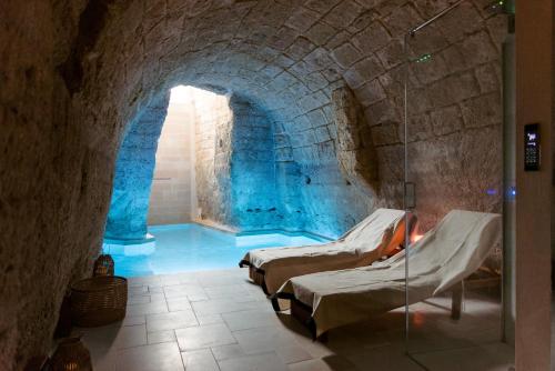 a room with three beds in a stone tunnel at Le Carasse Boutique Hotel in Mola di Bari
