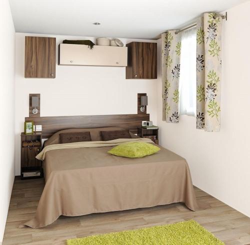 a bedroom with a bed with a green pillow on it at Camping Le Sainte Marie in Sainte-Marie-la-Mer
