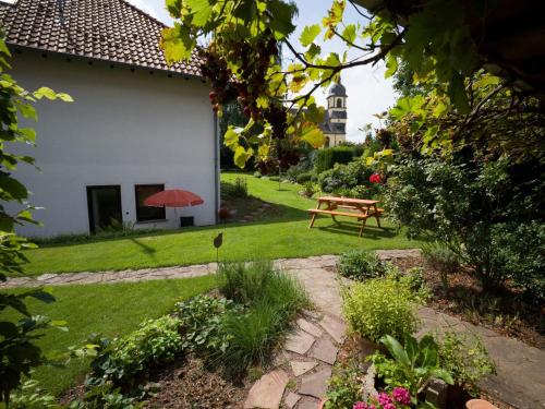 un giardino con panchina e ombrellone rosso di Haus Gartenstrasse a Merzig